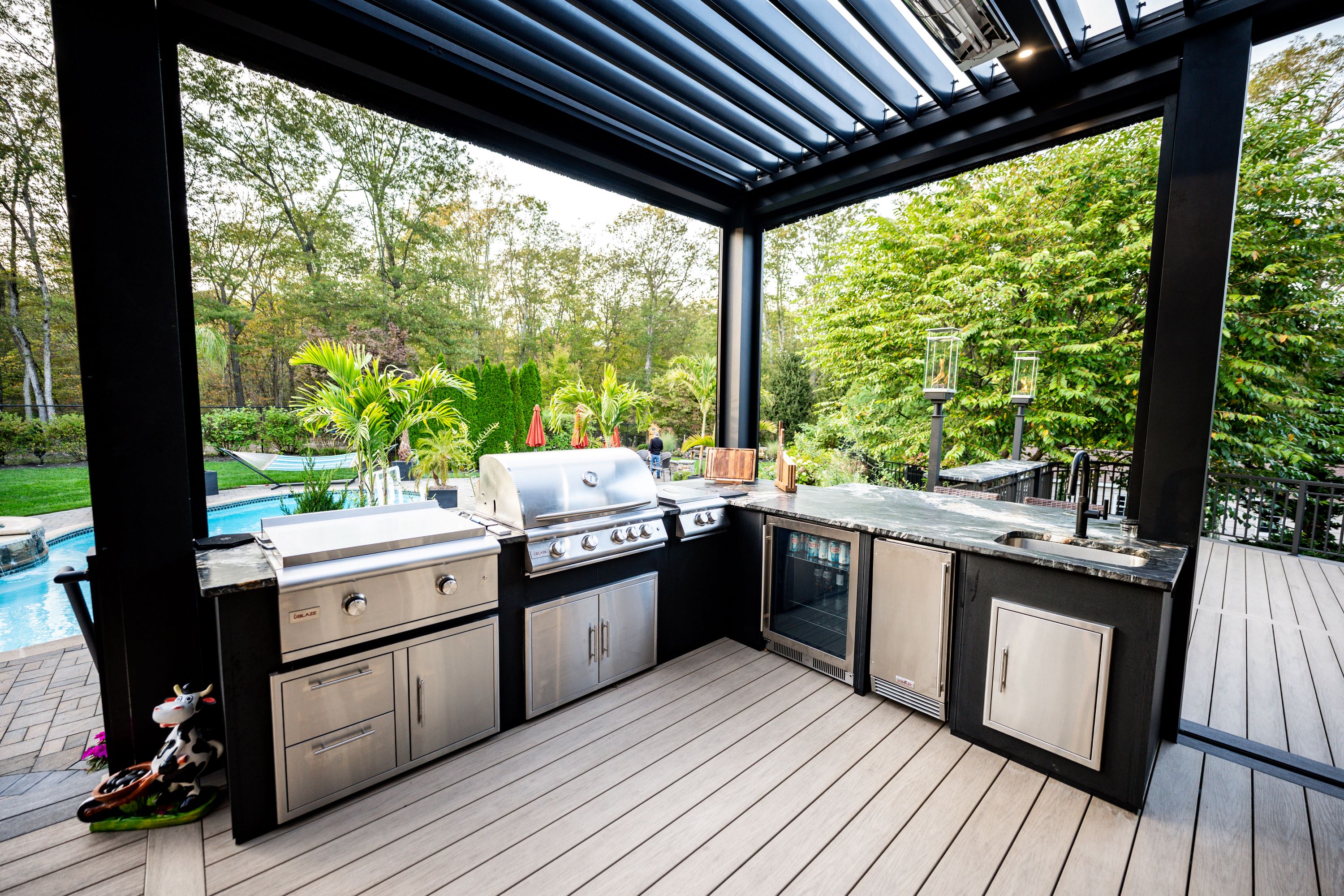 poolside outdoor kitchen with stainless steel appliances, beverage fridge, sink, and louvered pergola
