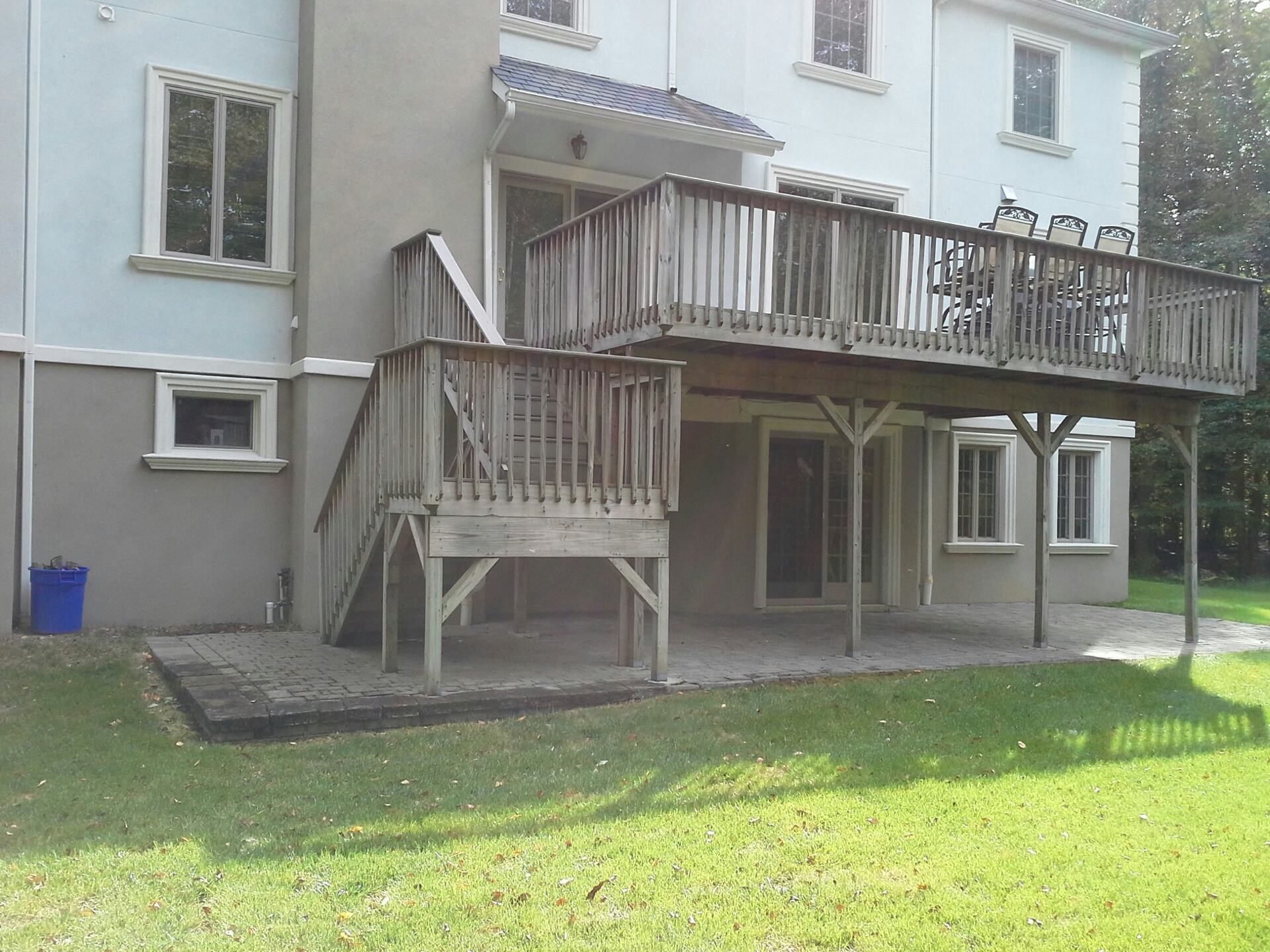 large elevated backyard deck with vinyl railings, extended platform framing, minimal visible bracing, and exposed support posts beneath a two-story home