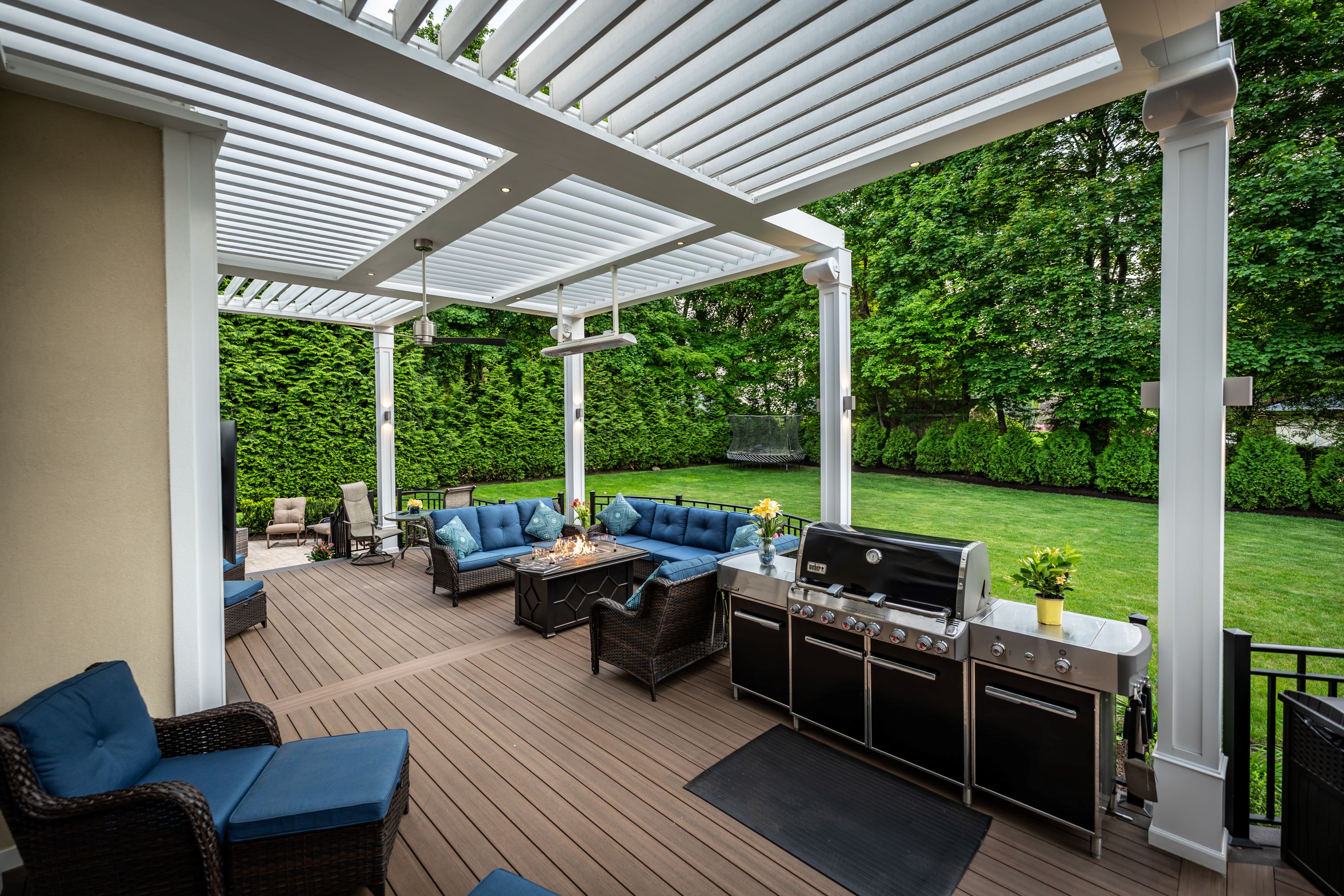 covered deck with grill, lounge seating, fire table, and adjustable louvered roof