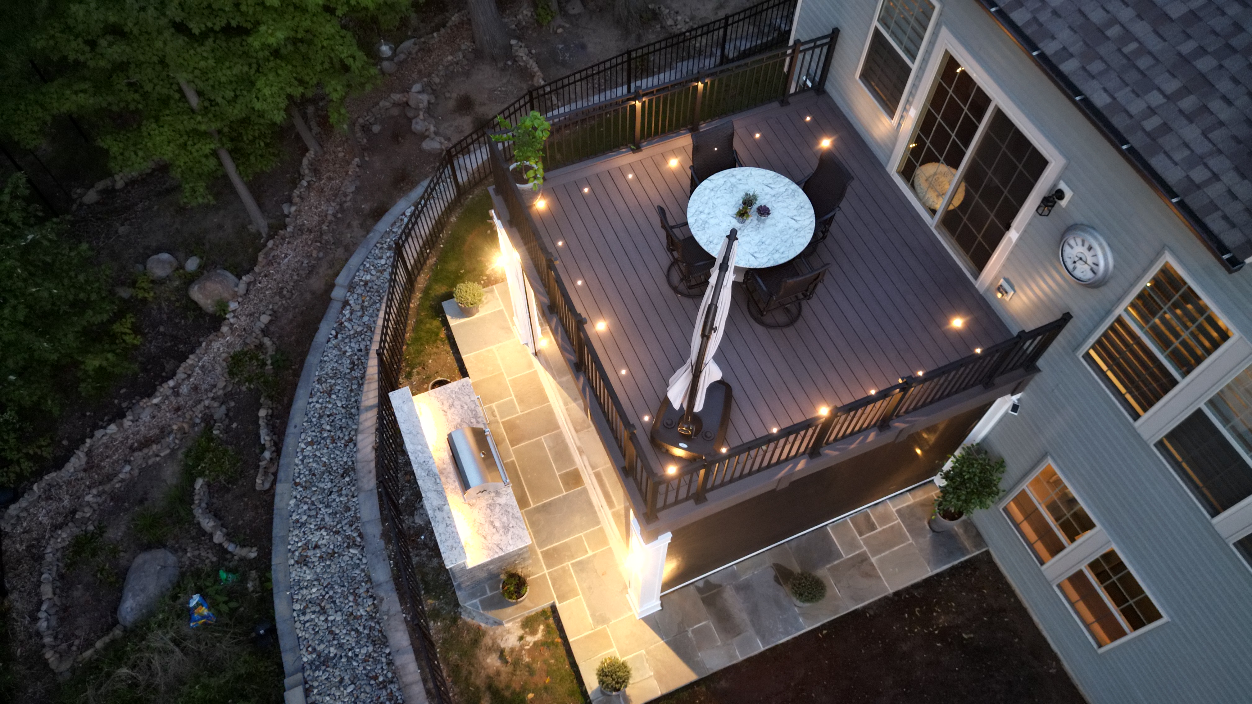 raised deck with outdoor lighting built into rail posts and floor, illuminating dining area and grill station below