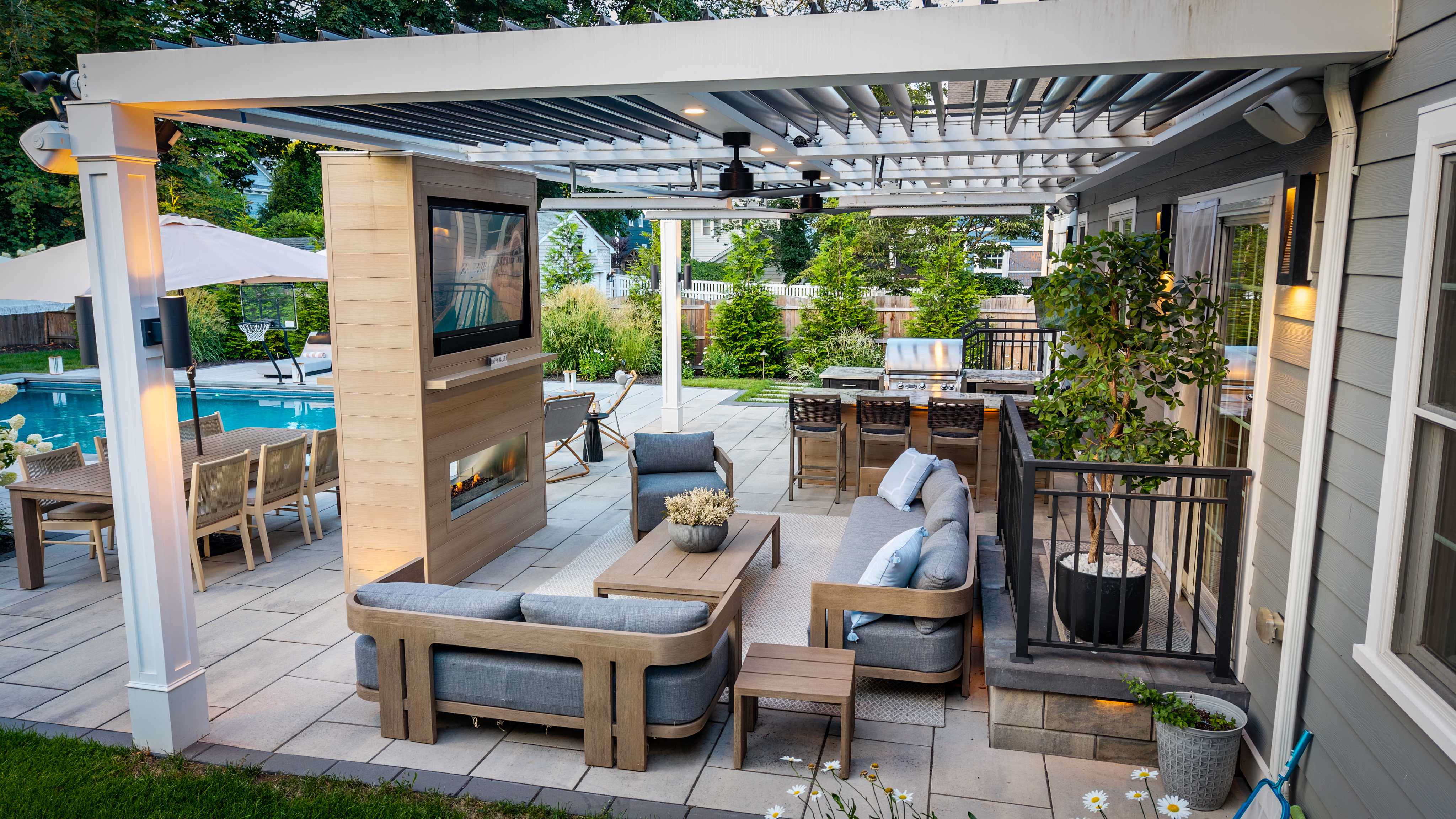 covered patio with lounge seating, fireplace, outdoor kitchen, and dining area beside a backyard pool