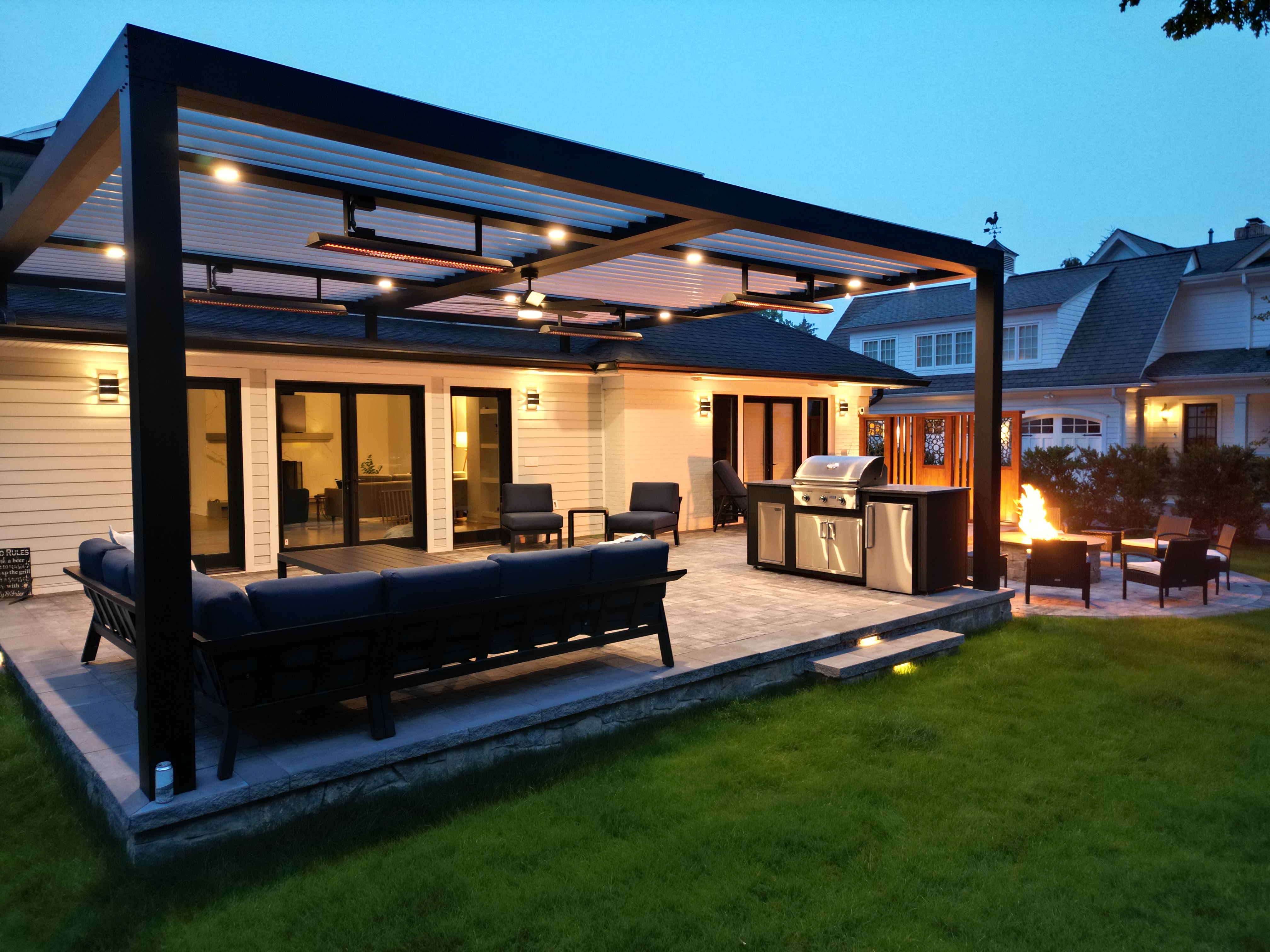covered backyard patio with louvered roof pergola, built-in outdoor kitchen, sectional seating, recessed lighting, and fire pit lounge area