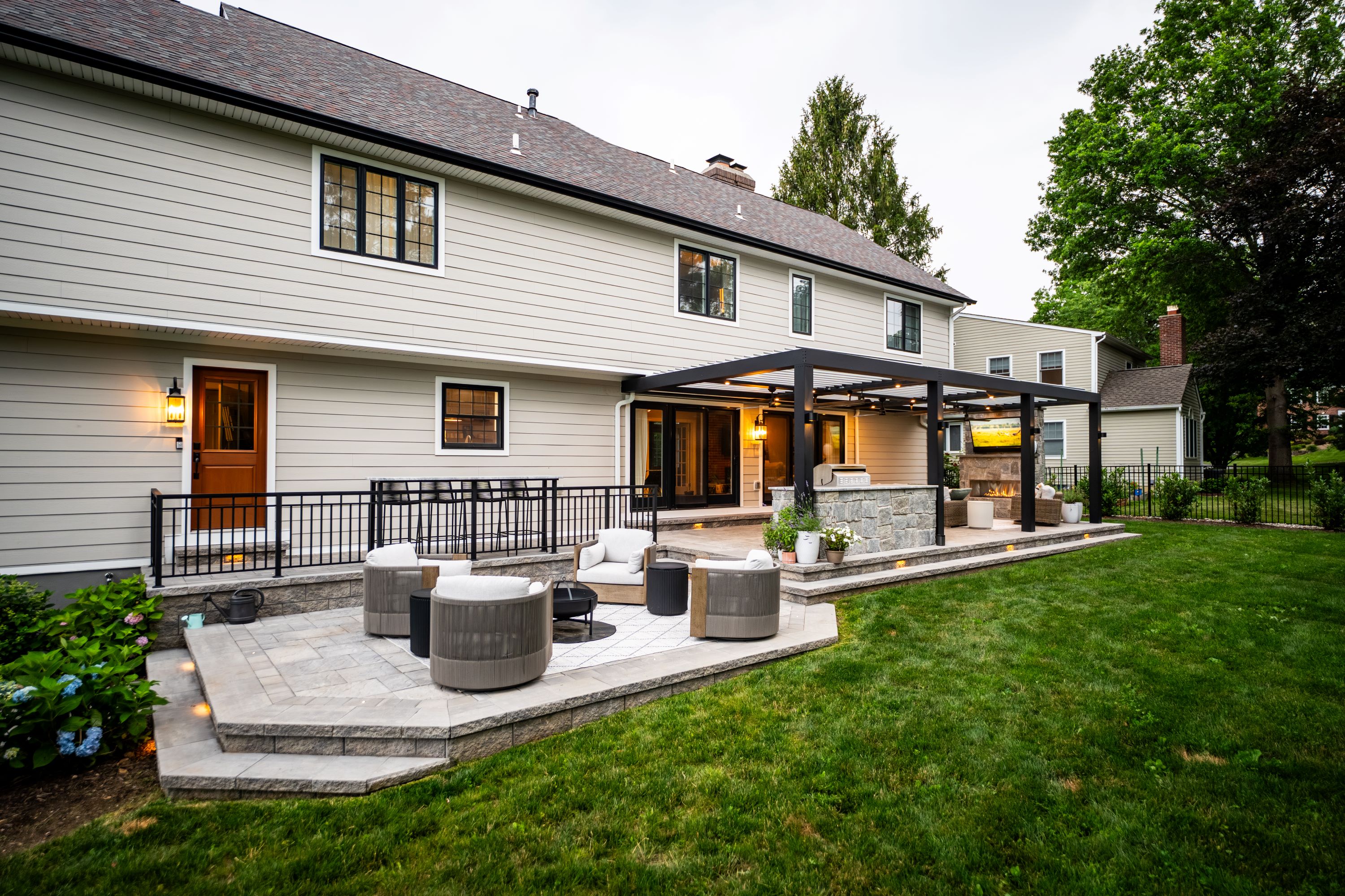 tiered backyard patio with lower seating area, covered lounge space, fireplace, and outdoor television