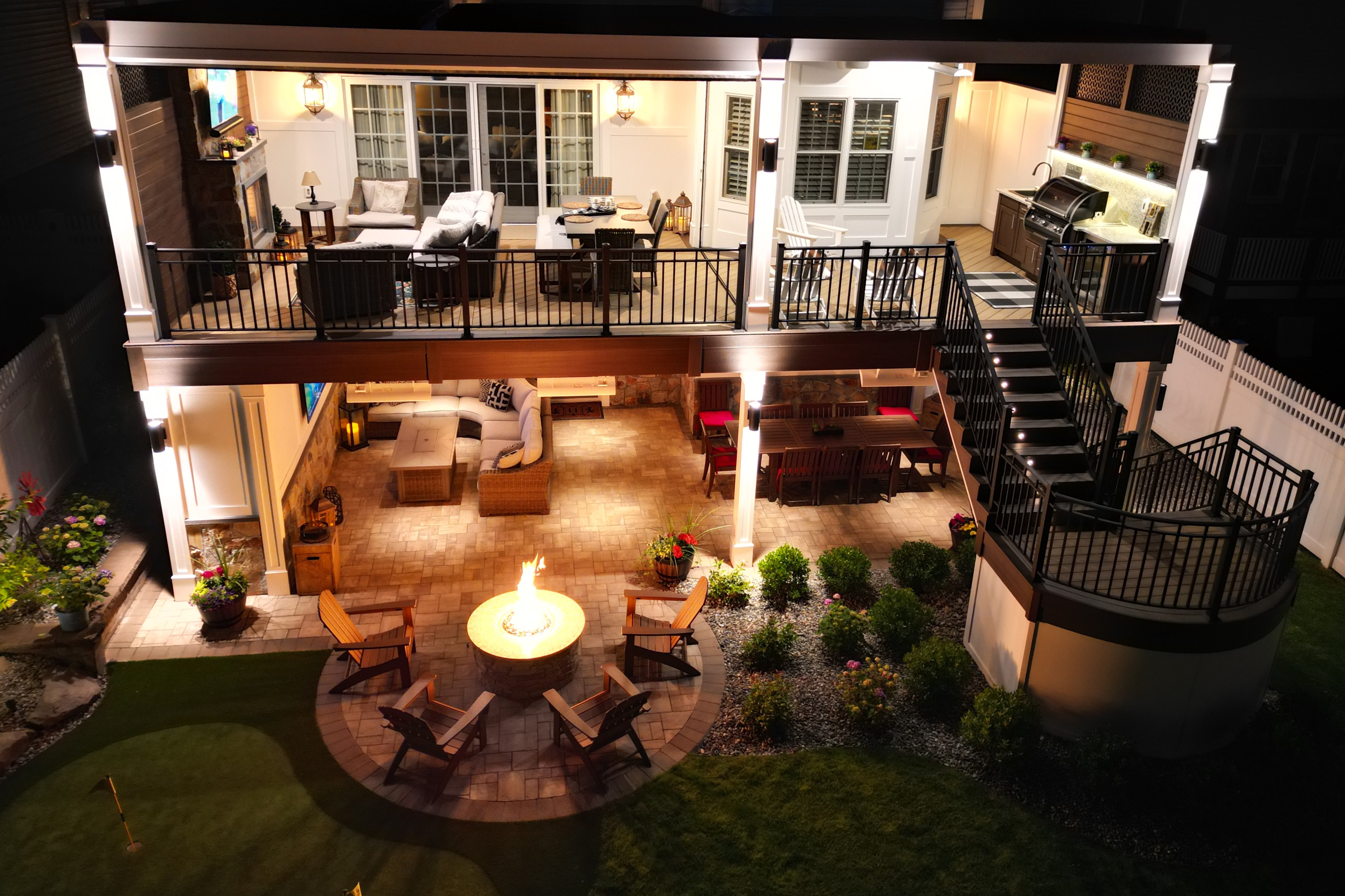 two-story outdoor living space with covered deck, finished under deck patio, and fire pit seating