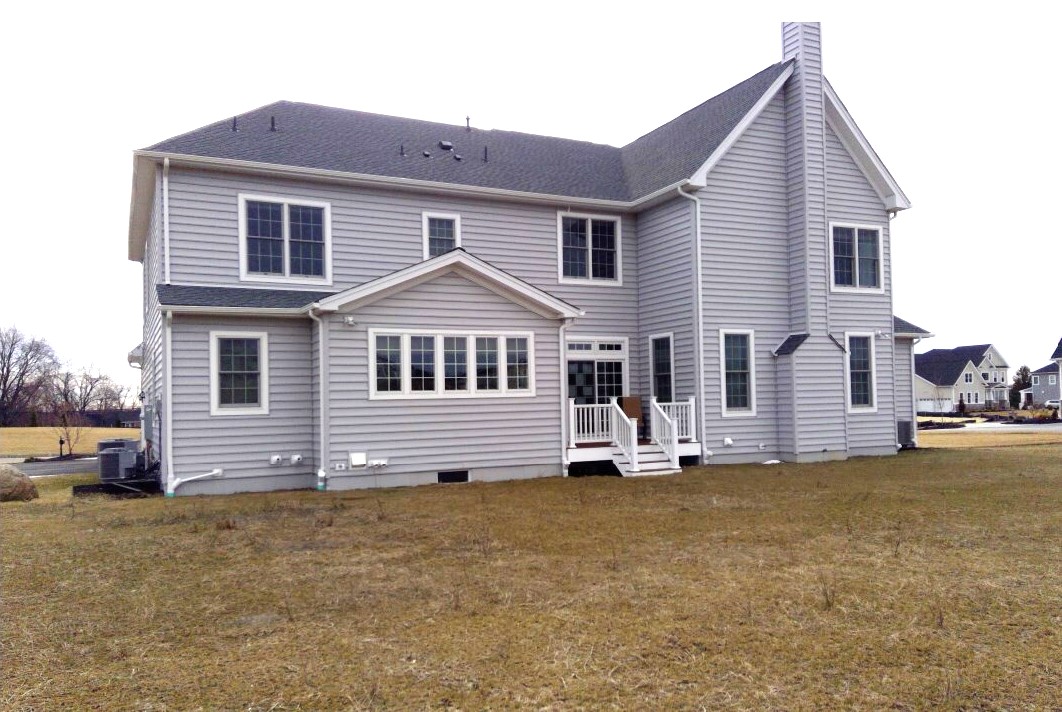 small elevated wood deck with white railings, exposed framing, and incomplete platform removal during backyard renovation on a two-story vinyl-sided home