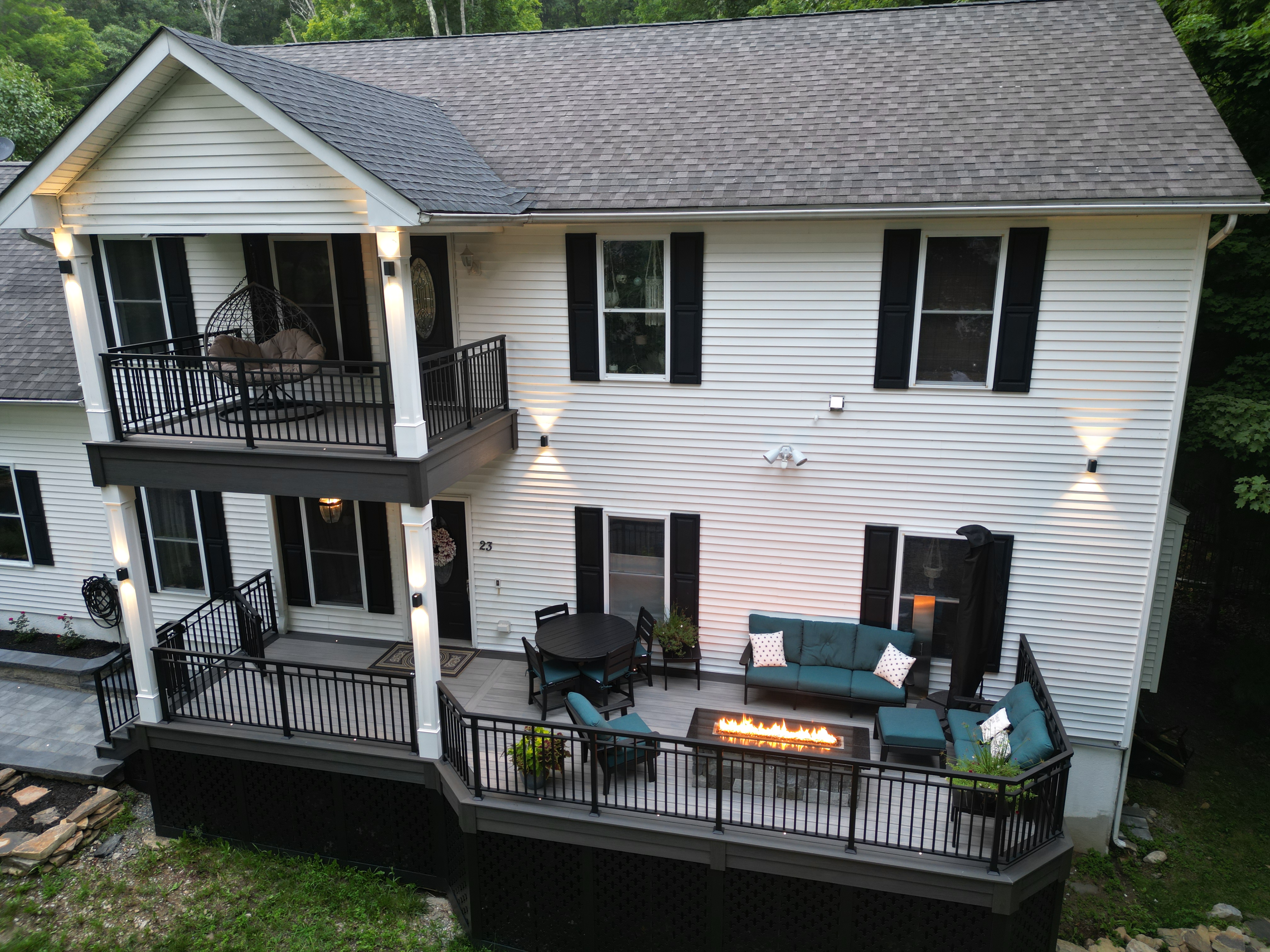 stacked deck with upper balcony seating and lower patio with outdoor sofa, dining table, and linear fire table