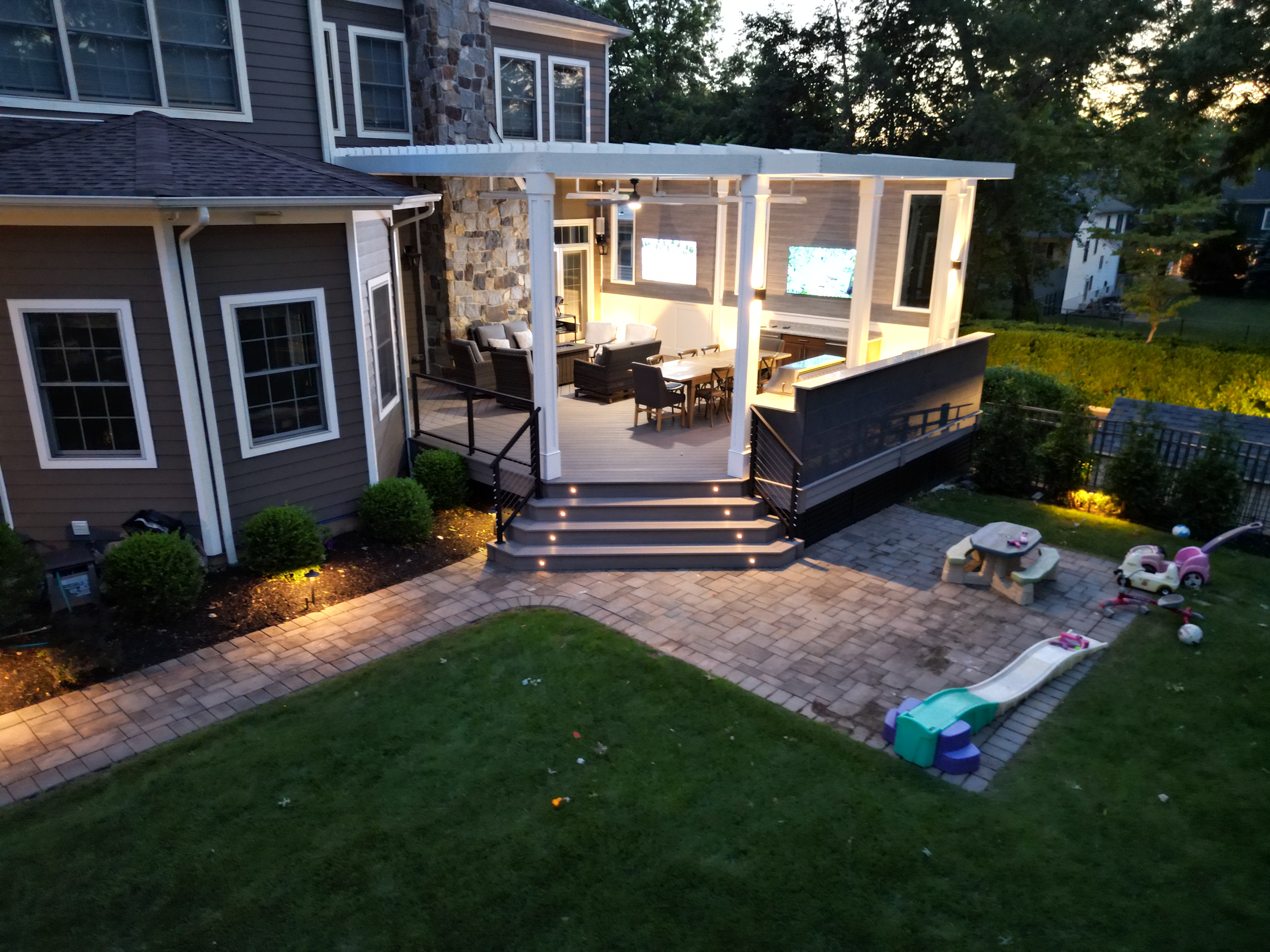modern backyard deck idea with motorized pergola, built-in step lighting, and covered lounge area