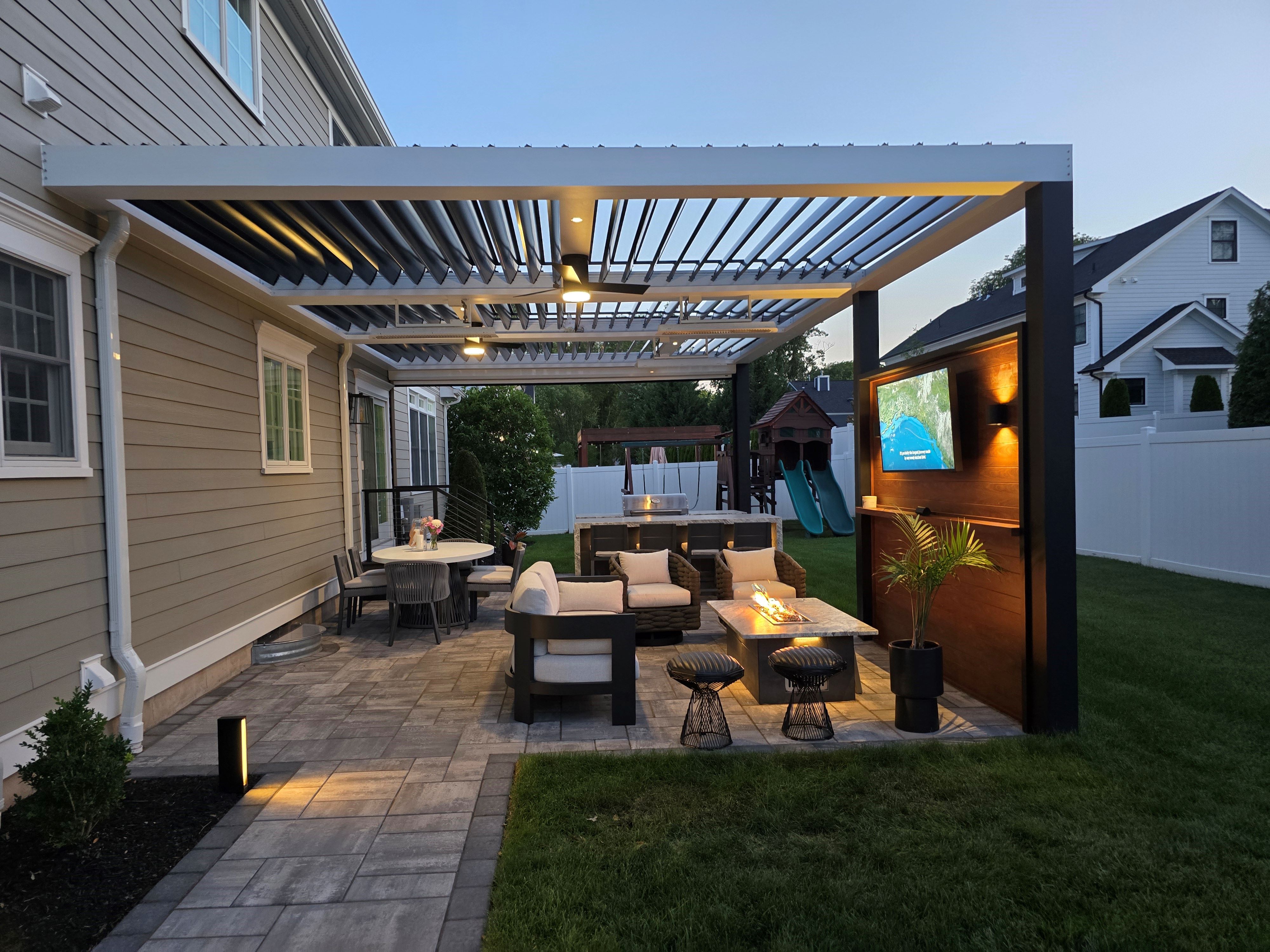 compact outdoor living space with louvered roof, dining area, lounge seating, fire table, and outdoor television