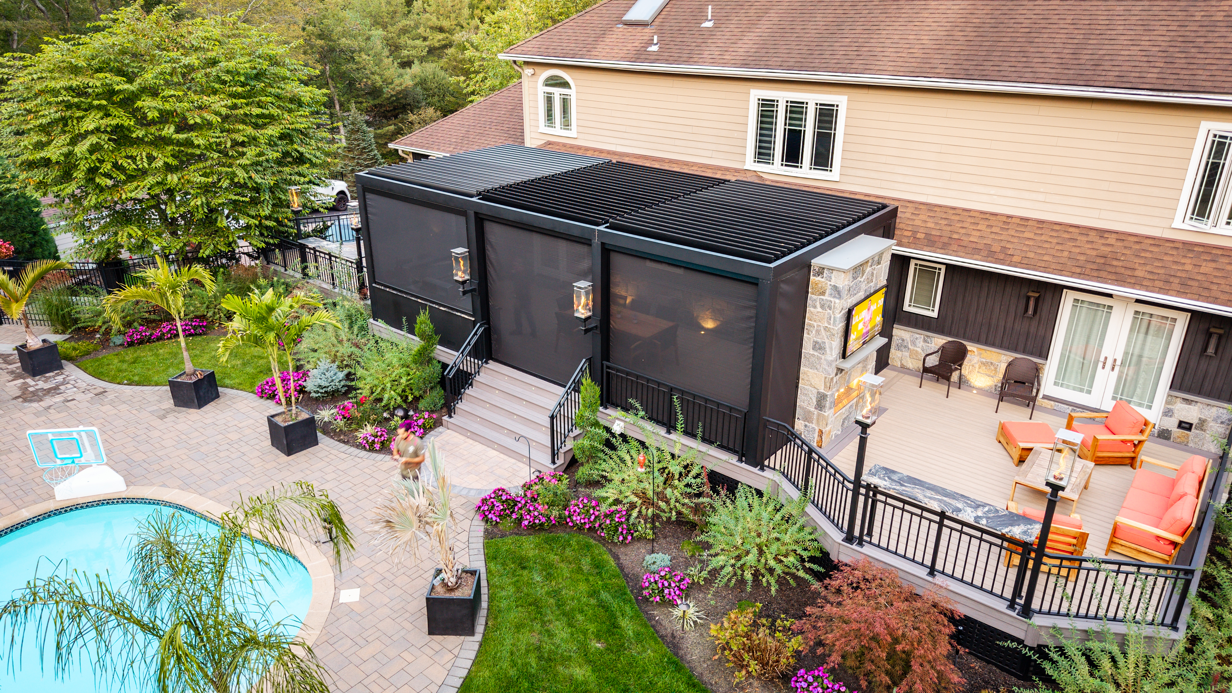 covered deck with motorized screens creating an enclosed outdoor living space overlooking a backyard pool