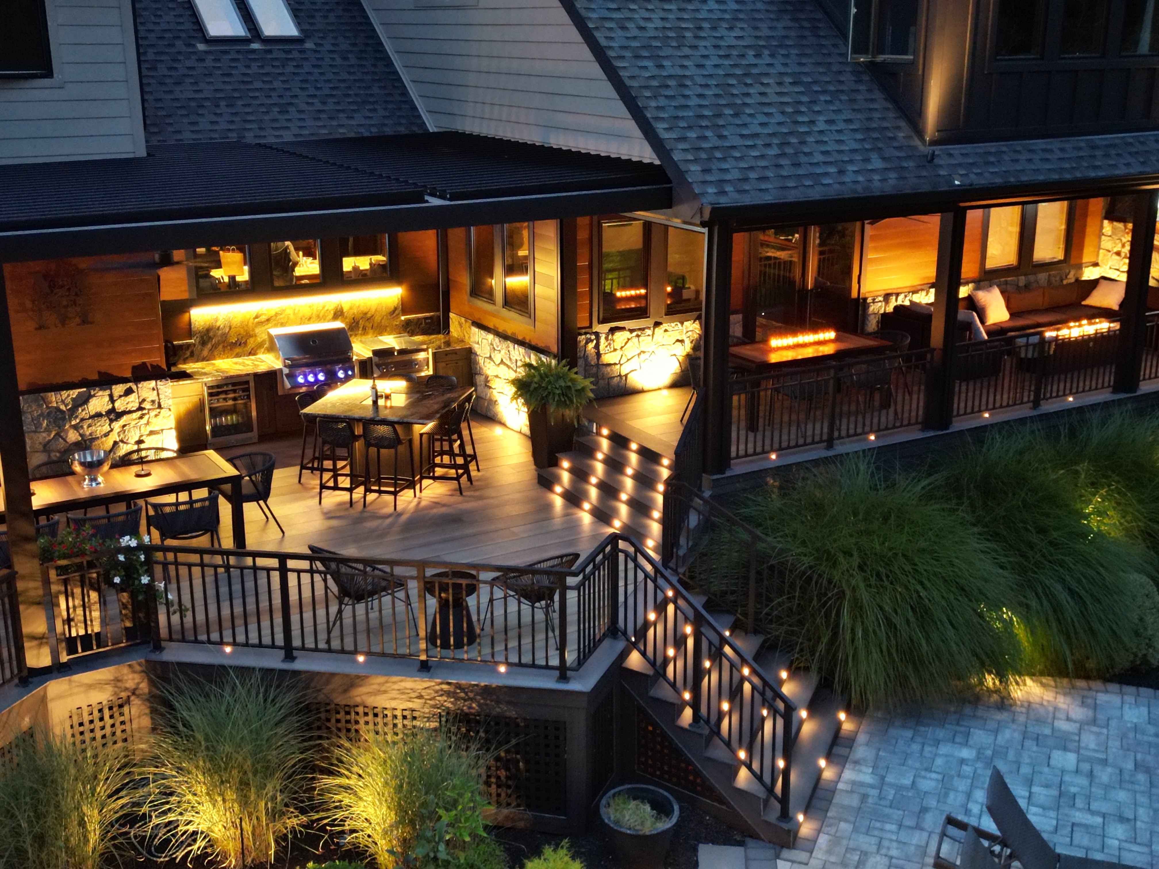 backyard pool and patio with landscape lighting accenting gardens, seating areas, and blue underwater pool lights