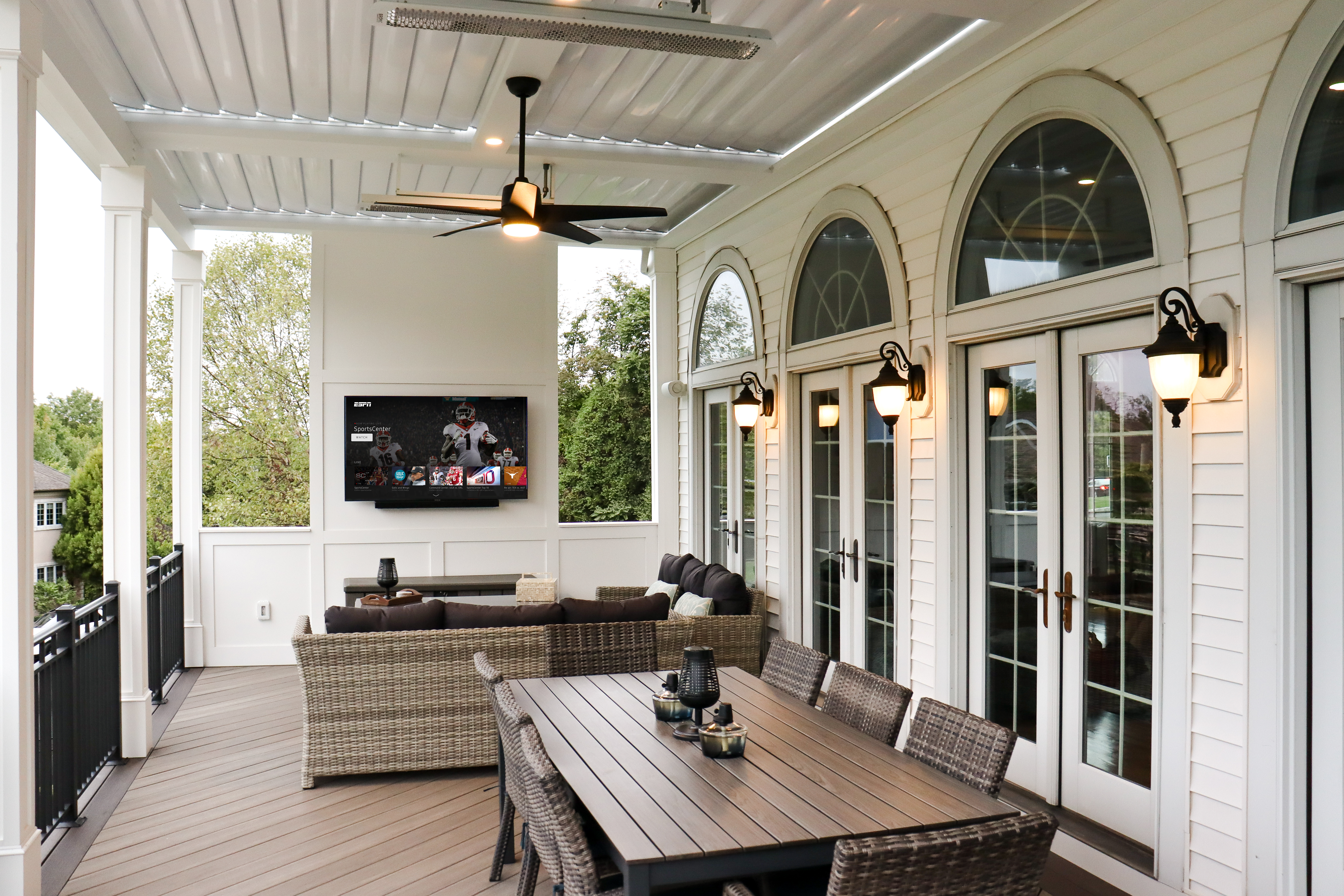 covered deck with louvered roof, outdoor TV wall, ceiling fans, pvc decking, and wicker furniture for lounge and dining
