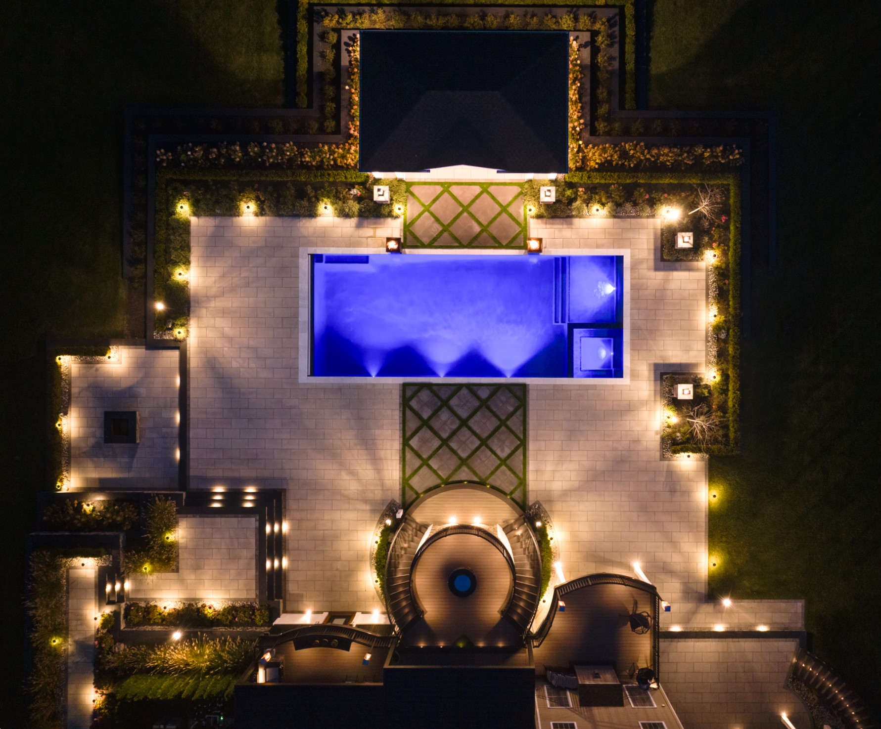 modern backyard pool with patio lighting and landscape lighting highlighting gardens, pathways, and seating areas