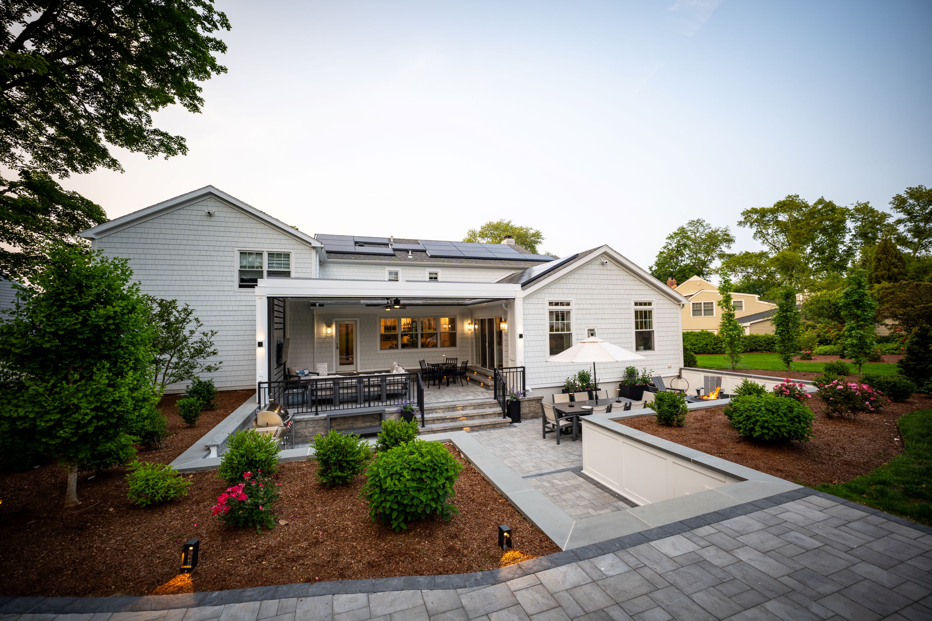 backyard patio with raised covered seating area, fire pit, outdoor kitchen, and retaining walls