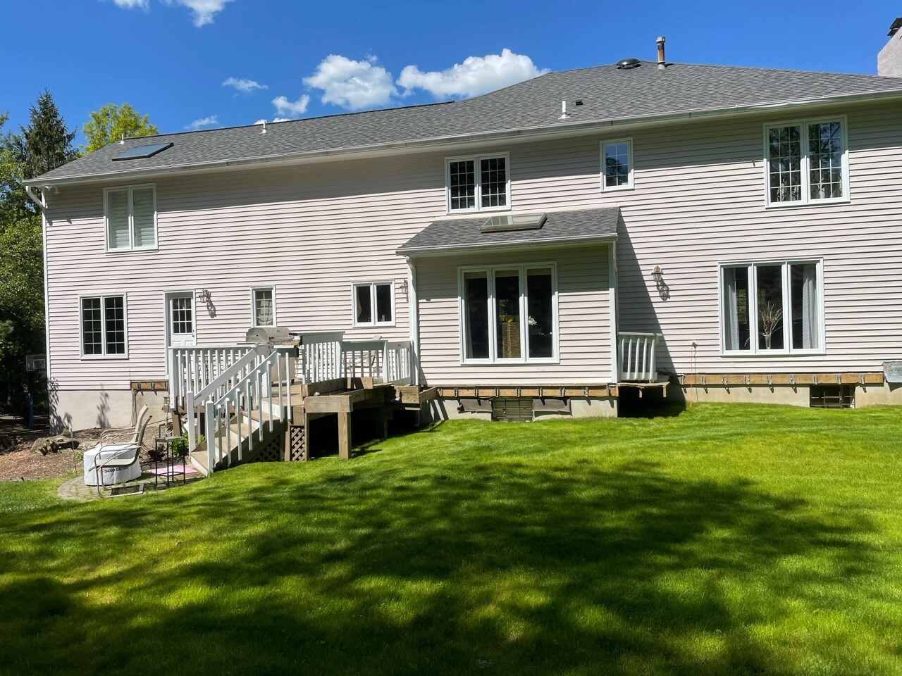 small elevated wood deck with white railings, exposed framing, and incomplete platform removal during backyard renovation on a two-story vinyl-sided home