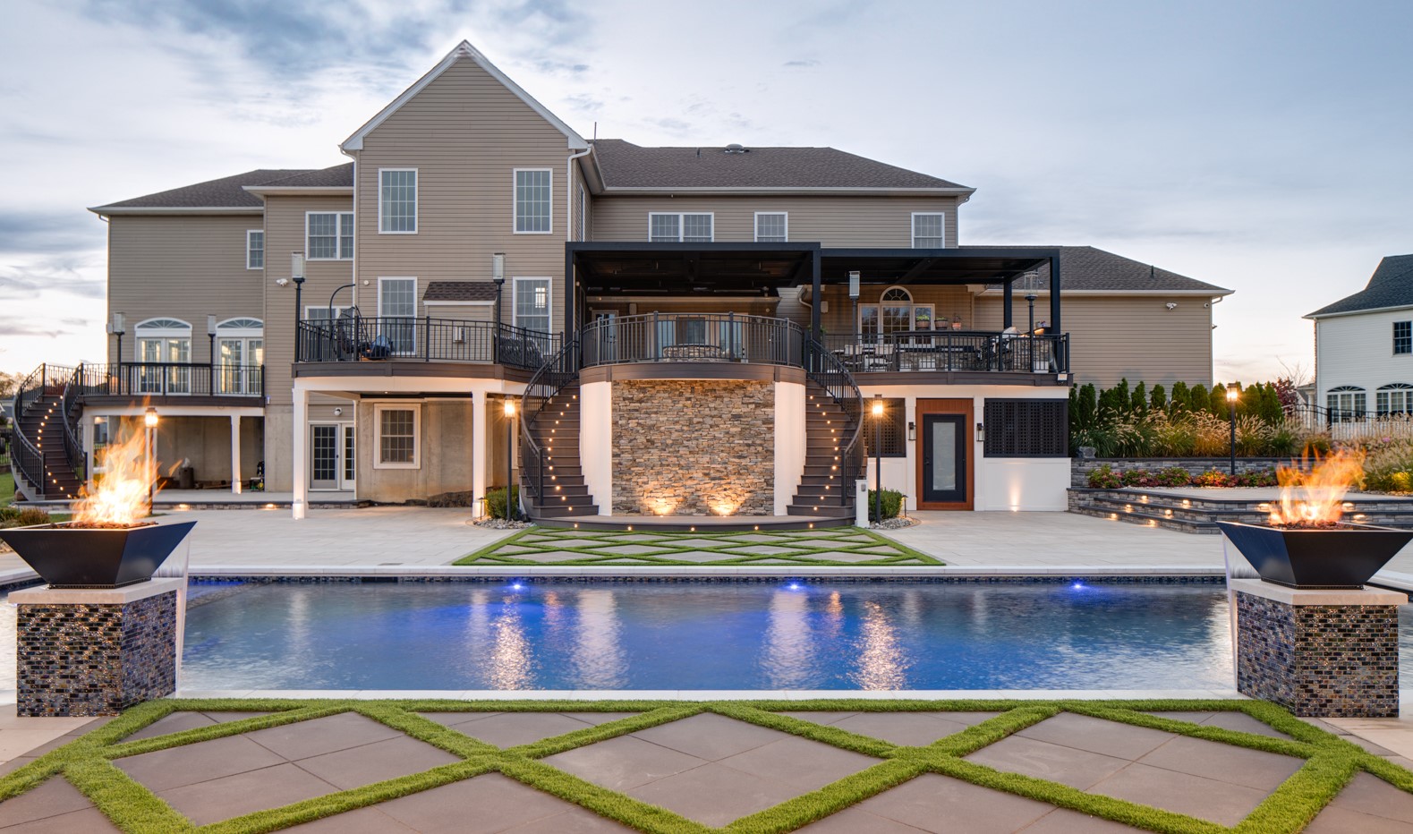 Backyard with pool, fire bowls, and large multi-level deck with stone accents and double staircases, Made by Deck Remodelers