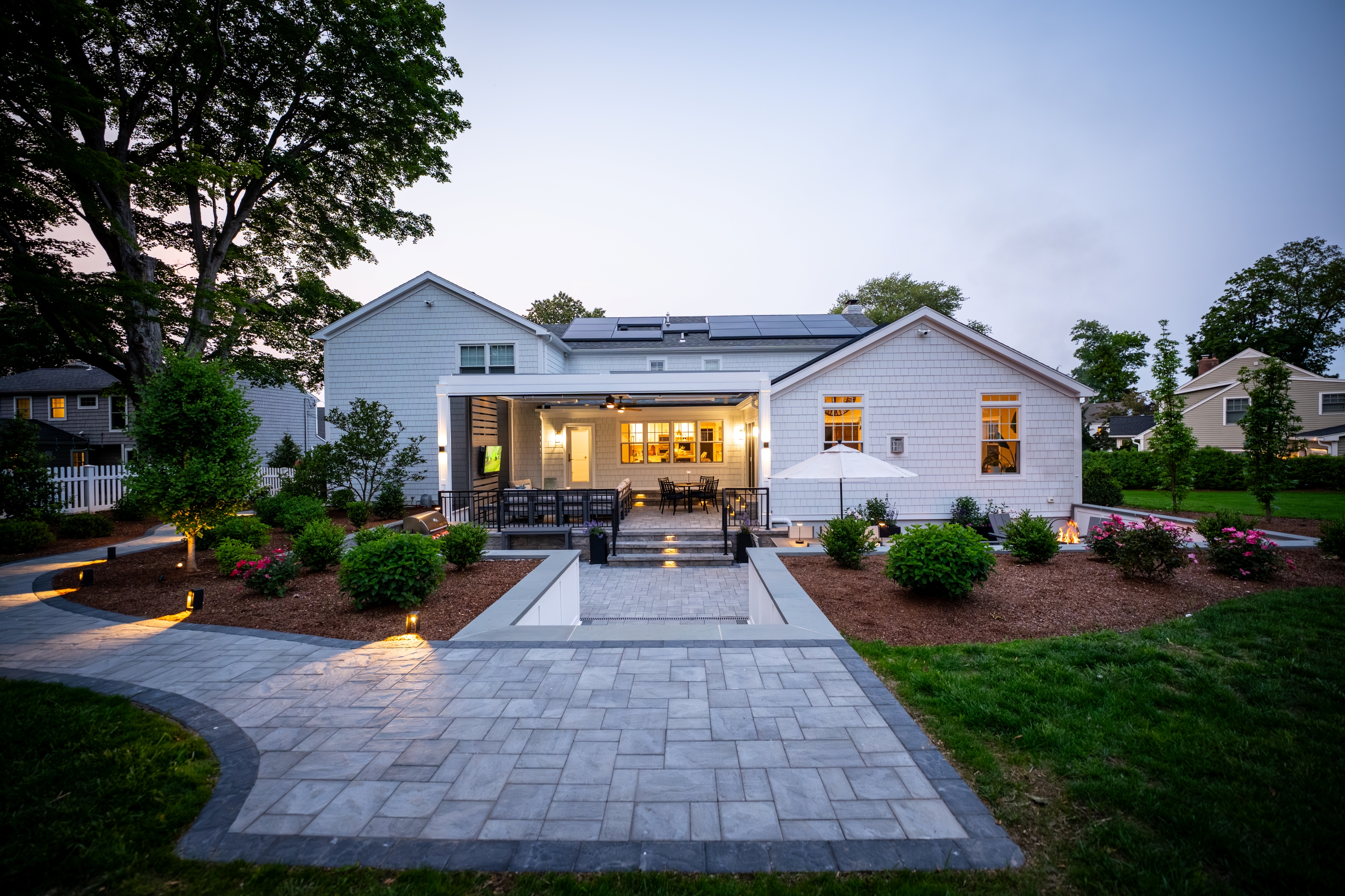 multi-level backyard patio with wide steps, surrounded by layered landscaping, garden beds, and soft outdoor lighting