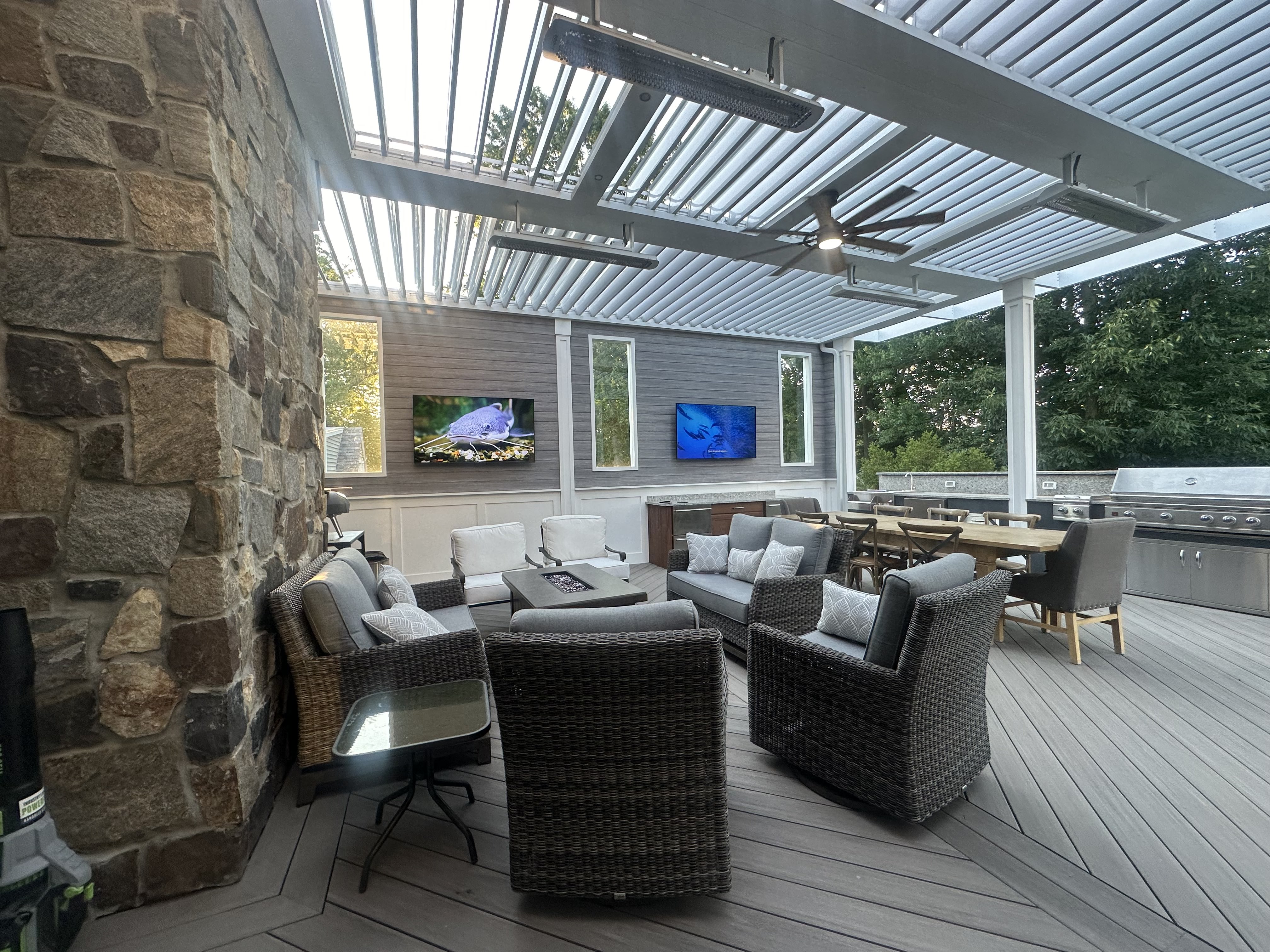 covered PVC deck with louvered roof, built-in heaters, outdoor kitchen, and lounge seating for year-round outdoor living