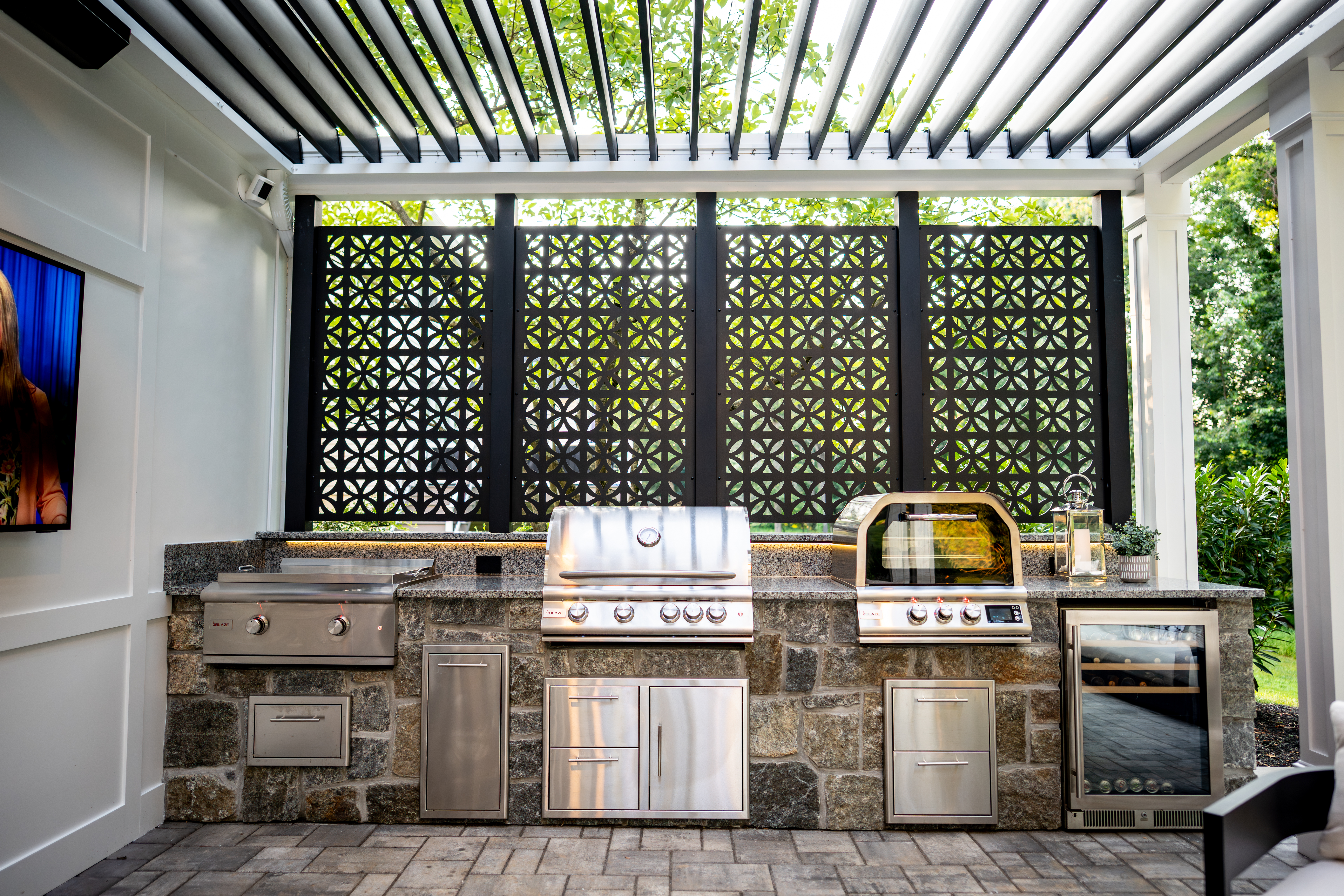 outdoor kitchen with built-in grill, pizza oven, storage, and wine fridge under a covered patio