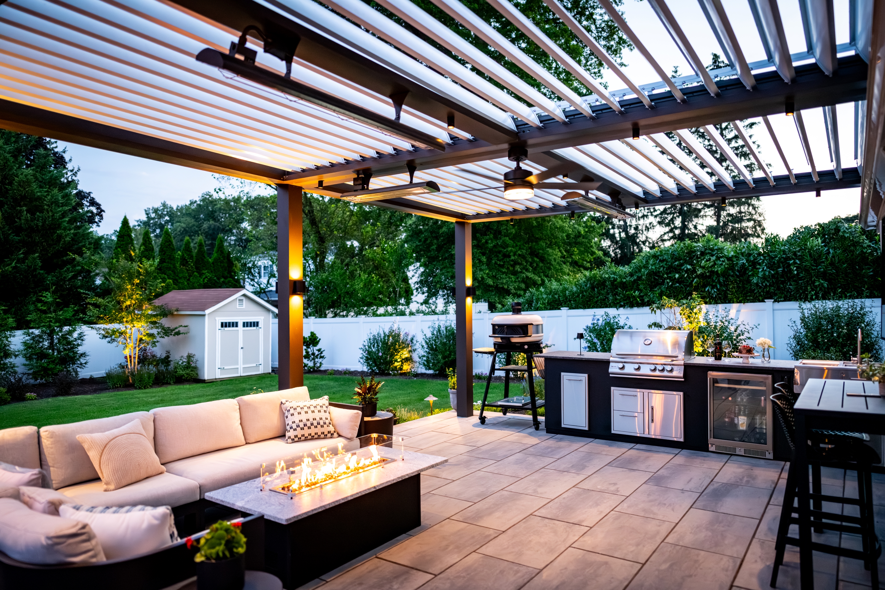 covered patio with louvered roof, outdoor kitchen, grill, bar seating, and fire table lounge area
